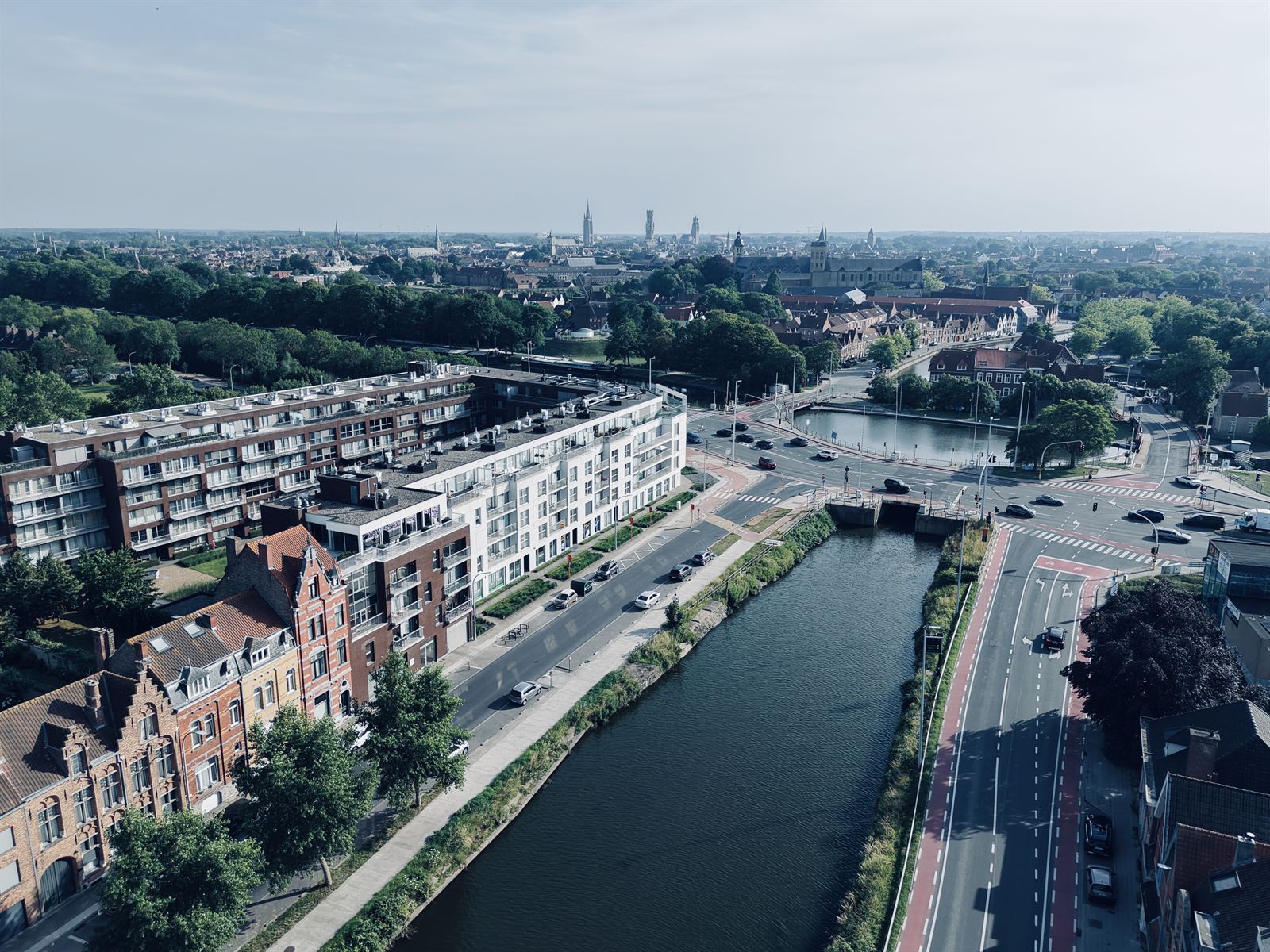 Luchtfoto van de praktijk aan de Damse Vaart, met de Brugse binnenstad aan de horizon